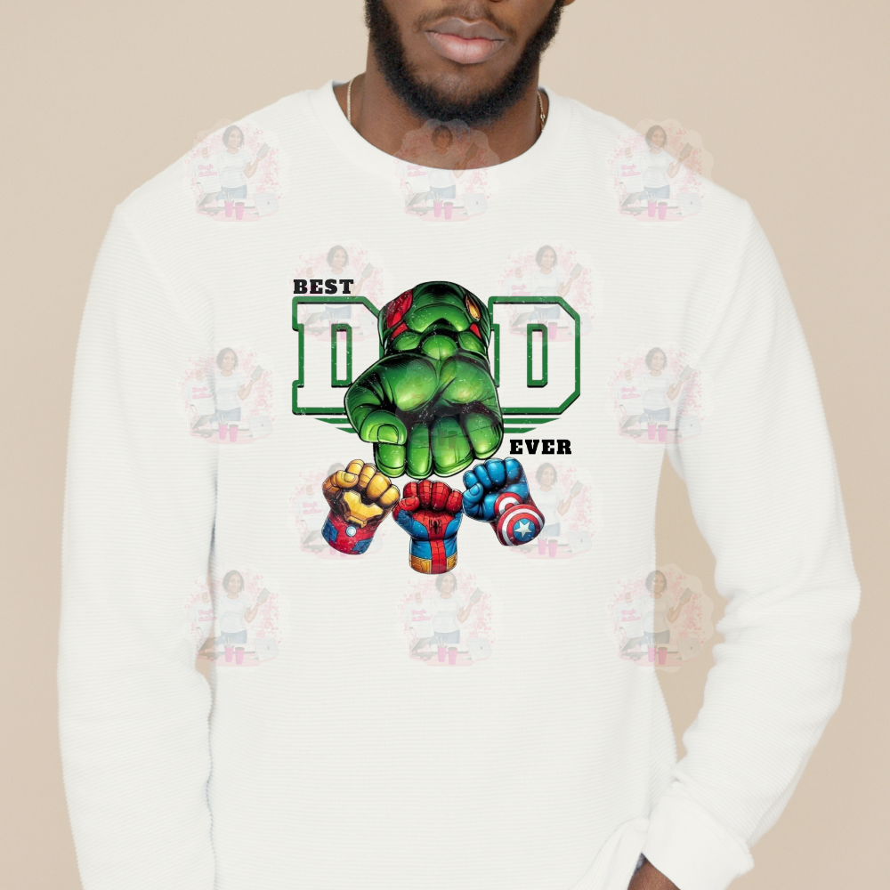 A person wearing a long sleeved t-shirt with a graphic design of a superhero character and the text 'BEST DAD EVER'.