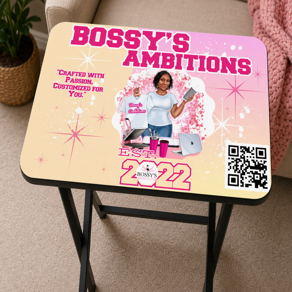 A customized rectangular tv table with a black wood frame, featuring a pink and beige graphic design with the text 'BOSSY'S AMBITIONS' and a photo of a woman holding a shirt and tumbler.