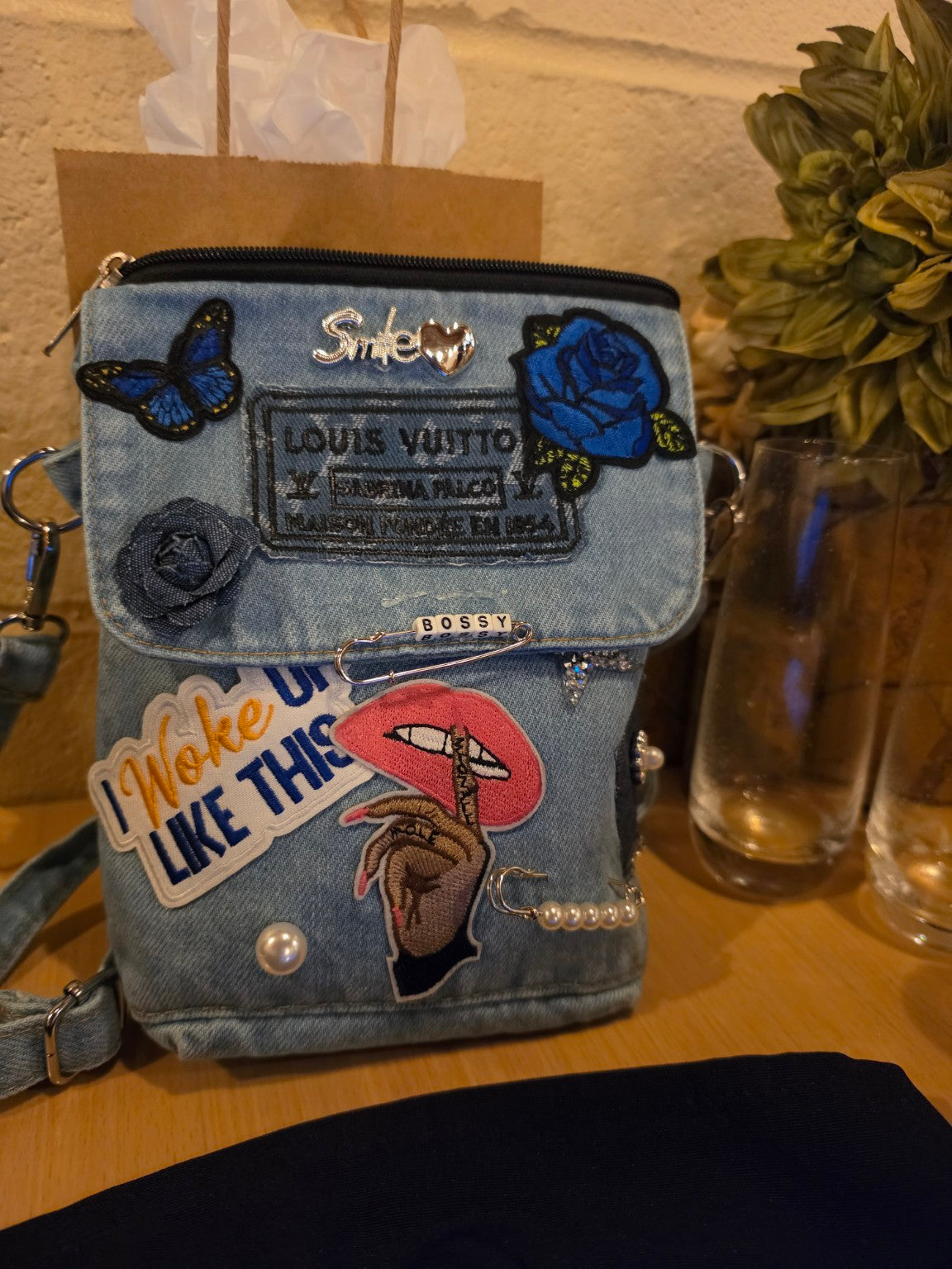 Custom light-wash denim patch purse with embroidered patches, charms, pearls, and decorative details